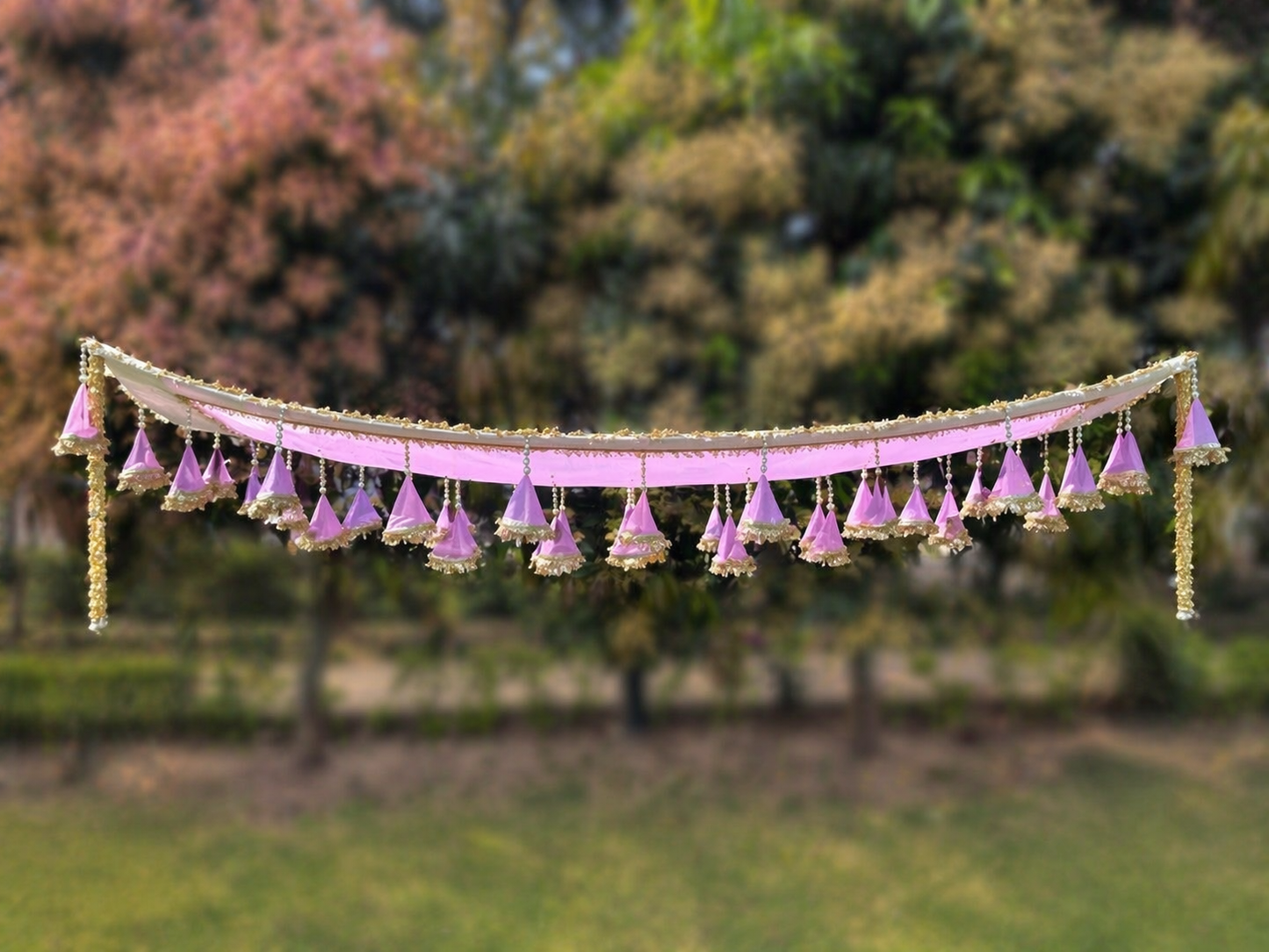 Decorative hanging with pink and gold elements against a blurred natural background