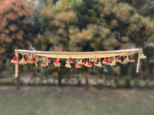 Decorative hanging with small red and gold elements against a blurred natural background