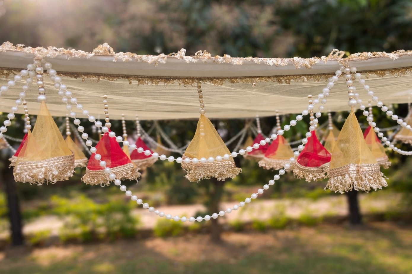 Decorative hanging elements with red and gold colors on a blurred natural background