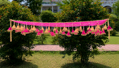 Decorative hanging lights with pink ribbons on a tree in a garden setting