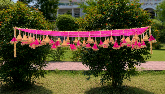 Decorative hanging lights with pink ribbons on a tree in a garden setting