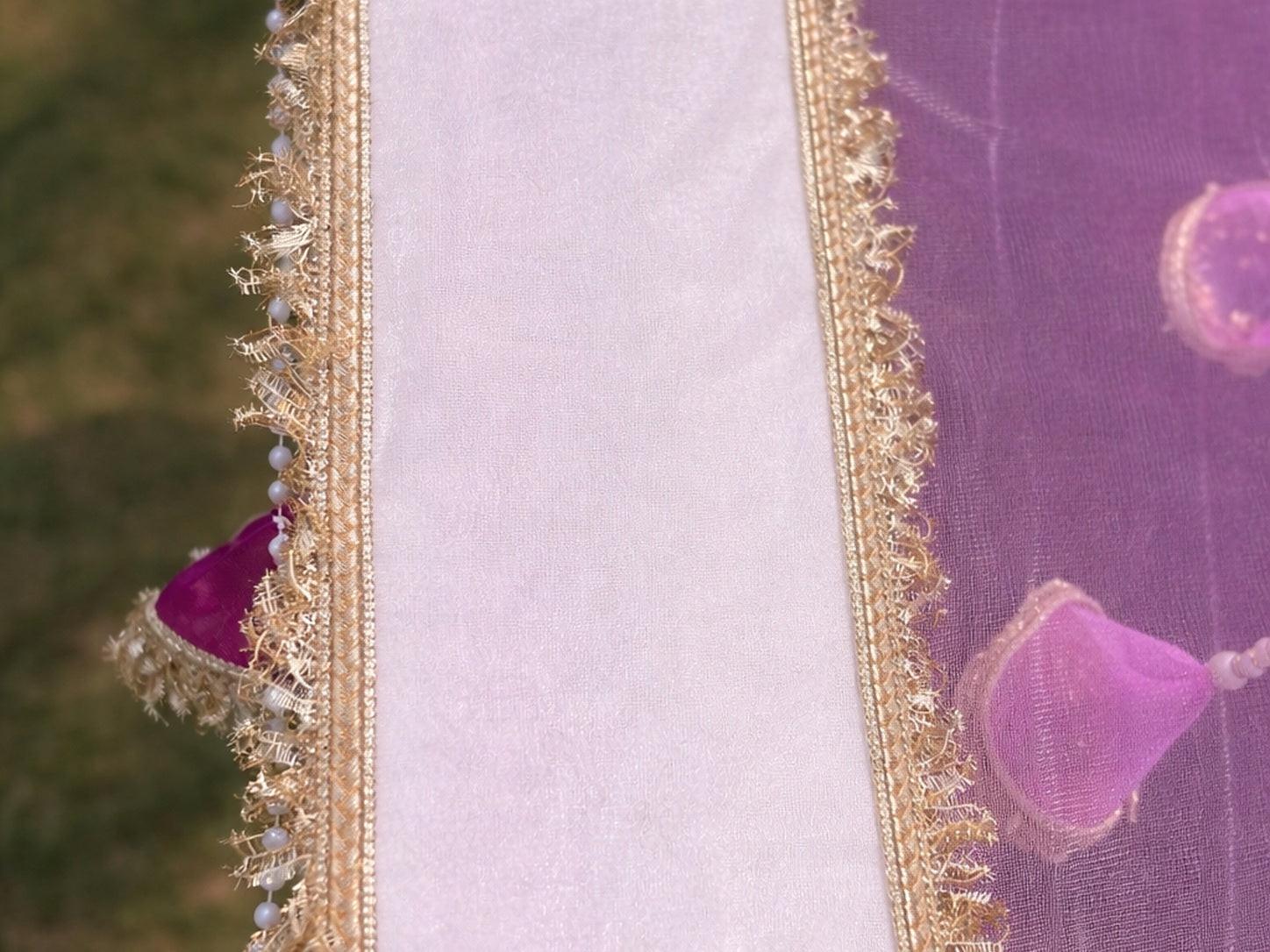 Close-up of a purple fabric with gold embroidery and decorative elements.