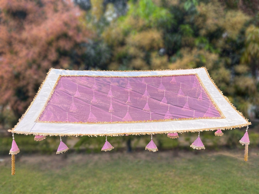 Decorative pink and white canopy with tassels against a natural background