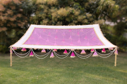 Decorative canopy with pink fabric and tassels on a grassy background