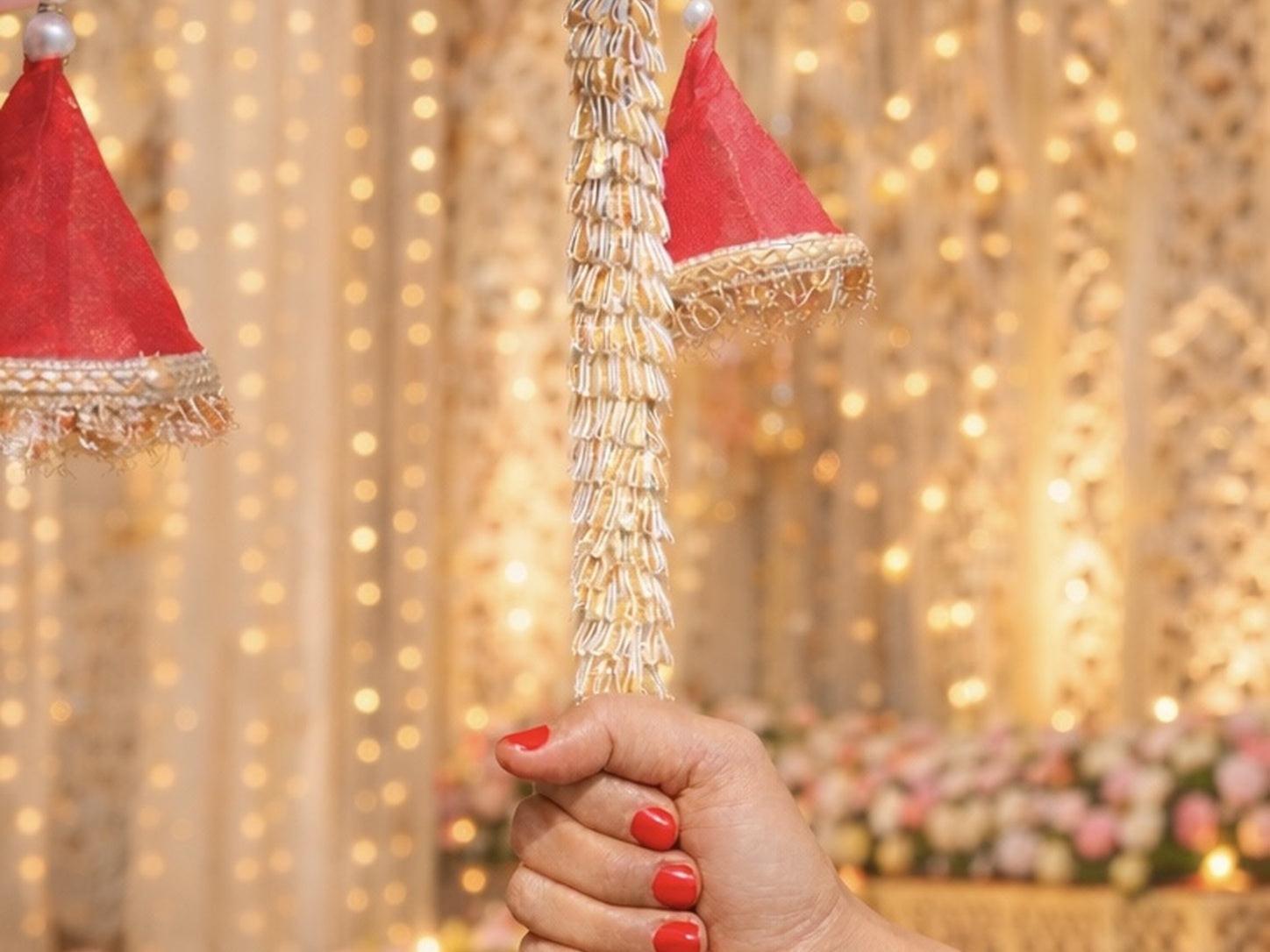 Hand holding a decorative string light with Santa hats against a festive background