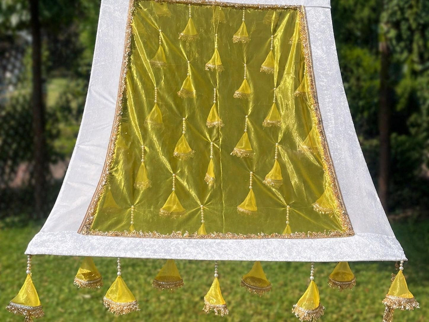 Decorative green fabric with gold patterns and tassels on a white background