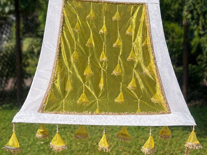 Decorative green fabric with gold patterns and tassels on a white background