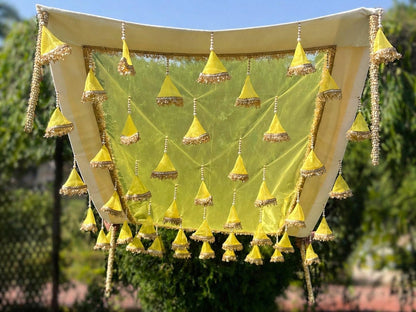 Decorative canopy with yellow triangular decorations against a green outdoor background