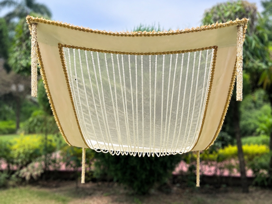 Beige hammock with tassels hanging outdoors against a green garden background