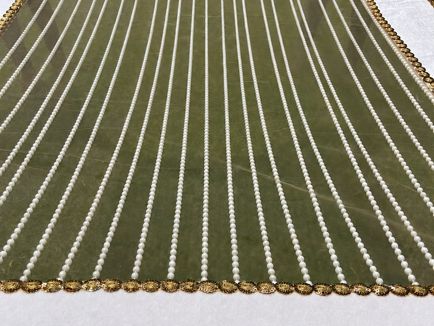 Green fabric with white vertical stripes and gold border on a white background