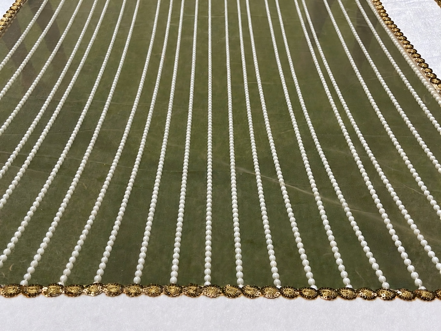 Green fabric with white vertical stripes and gold border on a white background