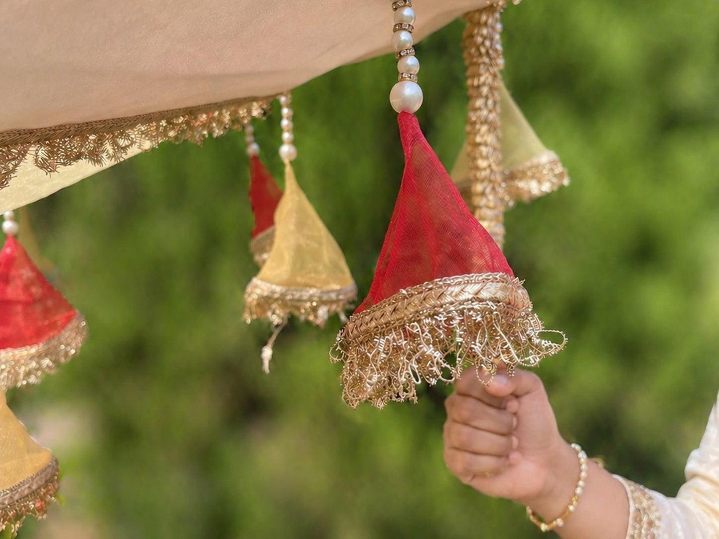 Decorative hanging elements with red and gold colors against a blurred green background