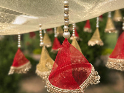 Decorative hanging elements with red and gold colors against a blurred green background