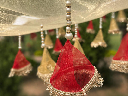 Decorative hanging elements with red and gold colors against a blurred green background