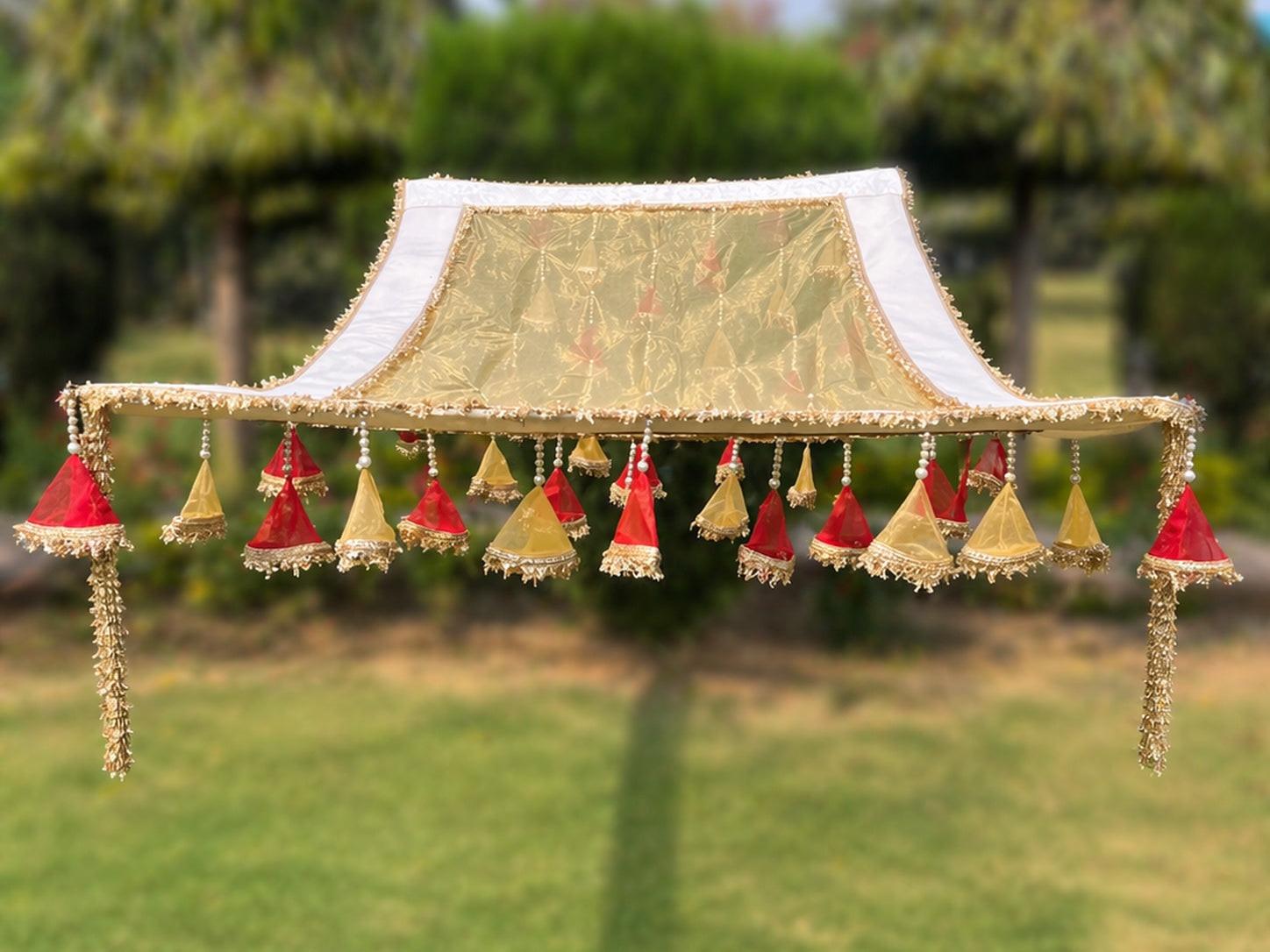 Decorative canopy with hanging ornaments on a blurred green outdoor background