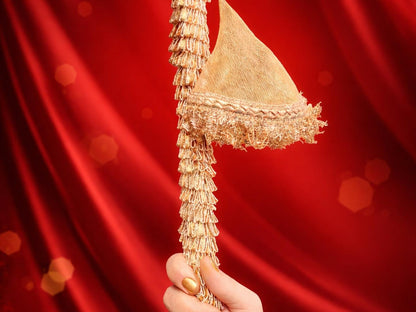 Gold decorative item held against a red curtain background